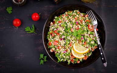 Tabbouleh salad. Traditional middle eastern or arab dish. Levantine vegetarian salad with parsley, mint, bulgur, tomato. Top view