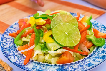 Cucumber salad with tomatoes and slices of lime on a plate