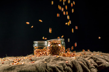 Fototapeta na wymiar corn grain falls on glass jars