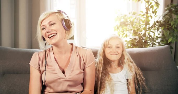 Joyful attractive mother and pretty preteen daughter having fun and listening to music. spending free time together