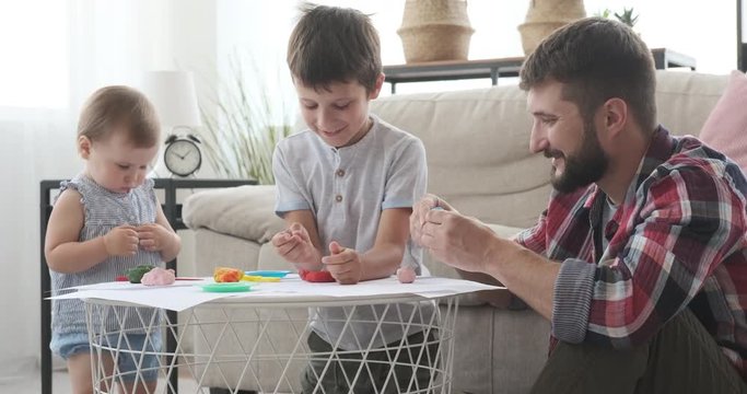 Father and children having fun playing with plasticine