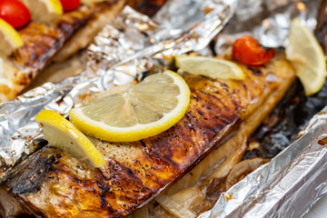 Fried mackerel on the foil with lemon and cherry tomatoes healthy delicious tasty food close up selective focus