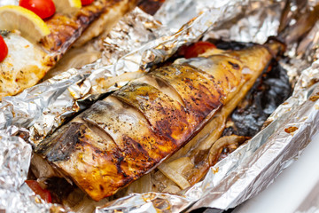 Obraz na płótnie Canvas Fried mackerel on the foil with lemon and cherry tomatoes healthy delicious tasty food close up selective focus
