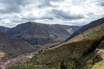 Fototapeta na wymiar Landscape with green Andean Mountains and Inca ruins on the hiking path in Pisac archeological park, Peru