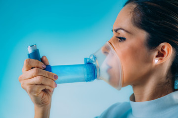 Woman Using Asthma Inhaler with Extension Tube