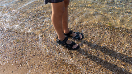 feet of a boy in sandals in the water