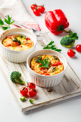 Vegetable frittata with broccoli, red bell pepper and red onion in cast iron skillet. View from above