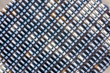 Aerial top view new cars lined up in the port for import export business logistic and transportation by ship in the open sea. New cars from the car factory parked at the port