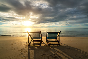 Two deckchairs on the beach at sunset with a tropical sea background. Travel and Vacation in Summer at sea.