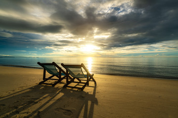 Two deckchairs on the beach at sunset with a tropical sea background. Travel and Vacation in Summer at sea.