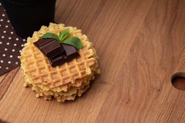 Belgian waffles with chunks on chocolate. Black mug on a brown polka dot napkin