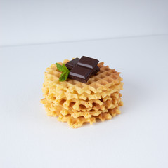 Crispy Belgian waffles with chocolate chips on a white textured surface