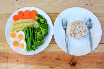 Clean food have brown rice, broccoli,carrot,Lentils,Baby corn,and egg in white disc on the wood table, healthy or vegetarian food concept Top view. 