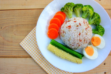 Clean food have brown rice, broccoli,carrot,Lentils,Baby corn,and egg in white disc on the wood table, healthy or vegetarian food concept Top view. 