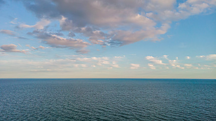 An aerial view of a majestic choppy blue water sea under a majestic blue sky and white clouds