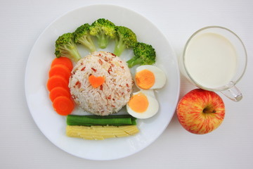 Clean food have brown rice,milk,apple broccoli,carrot,Lentils,Baby corn,and egg in white disc on white background, healthy or vegetarian food concept Top view. 