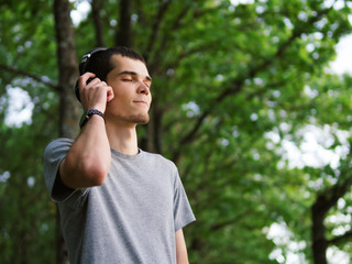 Beautiful man in headphones listening to music outdoor.