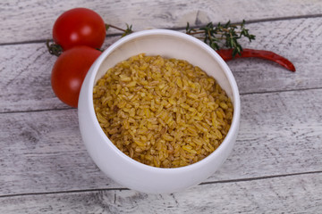 Raw bulgur in the bowl with tomatoes and garlic