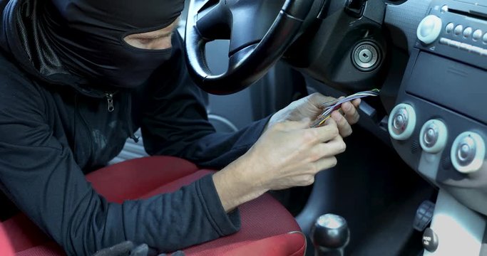 thief try to start and steal a car by connecting ignition wires. dolly shot