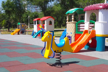 Multi-colored children's swings and slides in the sunny summer at the playground in the park.