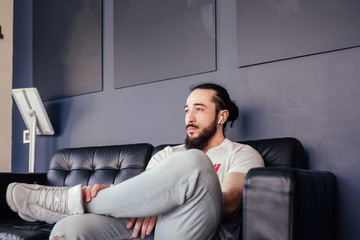 Handsome young man stylish hipster sitting on the sofa and looking aside. Concept of courageous...