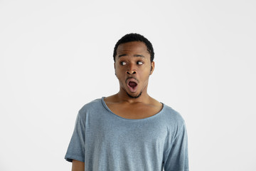 Beautiful male half-length portrait isolated on white studio background. Young emotional african-american man in blue shirt. Facial expression, human emotions, ad concept. Astonished, shocked, crazy