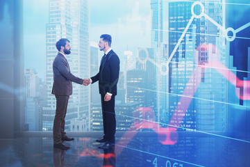 Businessmen shaking hands in office, graphs