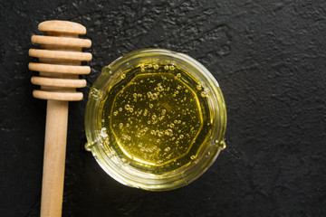 Spa concept with organic flower honey. Sweet healthy food in glass jar with wooden stick with copy space. Flat lay