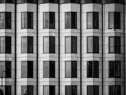 A black and white, abstract image of angular windows on the front of a modern building