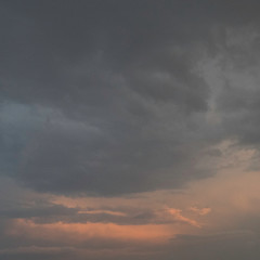 Dark grey clouds with orange sunlight before the thunderstorm starts.