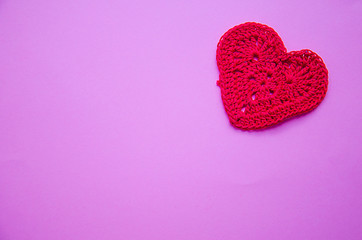 Obraz premium Knitted heart red on a pink purple background