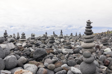 Fototapeta na wymiar Few stones pyramids on pebble ocean beach symbolizing stability, zen and harmony