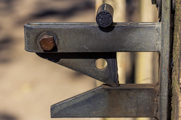 A common, metal gate latch takes on the appearance of a cartoon character when seen up close