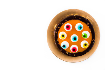 Halloween cake with candy eyes decoration isolated on white background. Top view. Copyspace