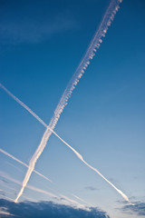 Contrails in blue evening sky forming a big X.