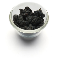dark raisins isolated in a glass plate