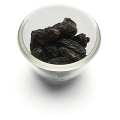 Black raisins large isolated in a glass plate