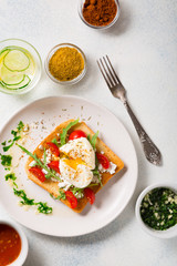 Breakfast. Poached egg on toasted toast, spices in bowls and a glass of lemon-cucumber water detox. top view with copy space