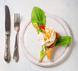 Triangular toast with poached egg on green spinach leaves and a round wooden board. top view with copy space