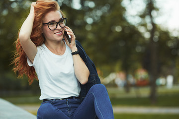 Beautiful red-haired girl with a beautiful figure and a phone in her hands. The girl communicates...
