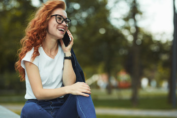 Beautiful red-haired girl with a beautiful figure and a phone in her hands. The girl communicates...