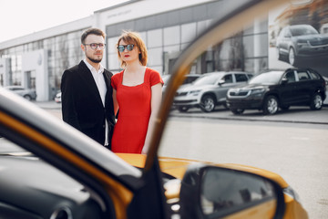 Fototapeta na wymiar Couple in a car salon. Family buying the car. Elegant woman with her husband.