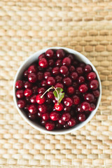 A plate full of fresh cherries on a natural wicker napkin
