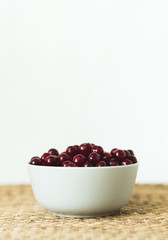 A plate full of fresh cherries on a natural wicker napkin