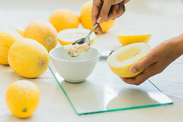 Melon berries on the kitchen table, hands cut melon into halves .