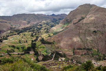 Landscape with green Andean Mountains and Inca ruins on the hiking path in Pisac archeological park, Peru
