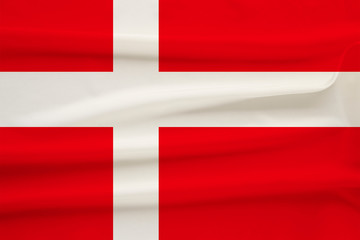 The national flag of the country of Denmark on the gentle silk with folds from the wind, the concept of travel, immigration, politics, copy space, close-up