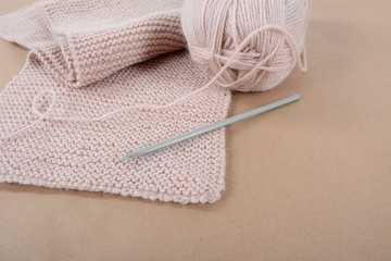 Skein of wool and a knitted scarf of beige thread.