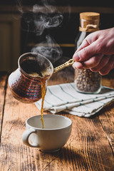 Pouring turkish coffee into white cup