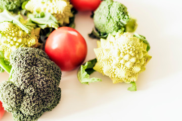 Ripe vegetables tomatoes romanesco broccoli on white wooden background with copy space for your text.